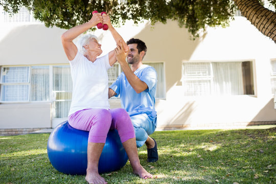Nurse helping senior woman doing exercises 