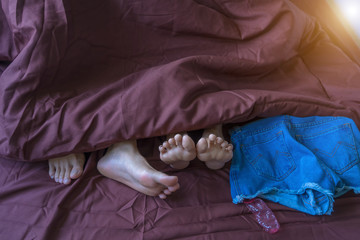 Close up couple feet lying in bed.