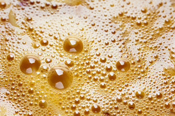 abstract background of fresh beaten chicken egg yolks surface with bubbles texture orange background, Close up .