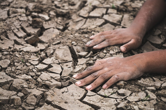 Hand on ground cracked dry due to drought, food shortages and water,  Concept drought and crisis environment.