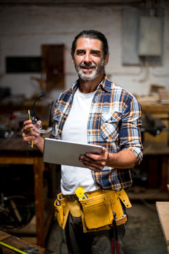 Carpenter using digital tablet in workshop