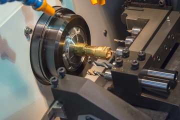 Fototapeta na wymiar The CNC lathe machine cutting the brass shaft with the drill tool.