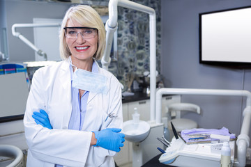 Portrait of smiling dentist standing with arms crossed