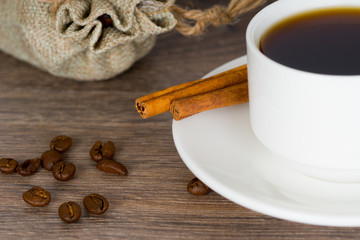 white cup of coffee, jute bag with organic coffee beans