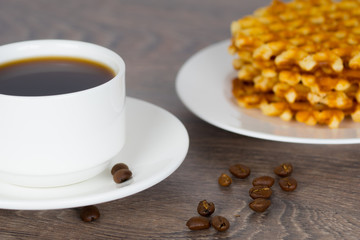 coffee cup with stack of belgian round waffles on wooden table