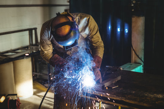 Welder welding metal in workshop