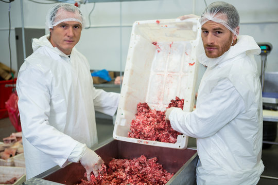 Portrait of butchers emptying minced meat in meat mincing machine