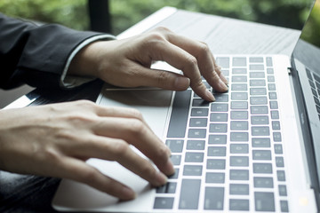 Blogger hands typing on laptop keyboard for writing about business and financial concepts and blogging about other technology topics.  White laptop with black keys and business suit with hands.