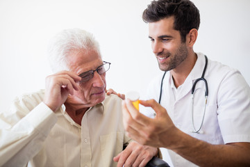 Nurse giving pills to senior man
