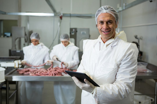 Smiling butcher using digital tablet