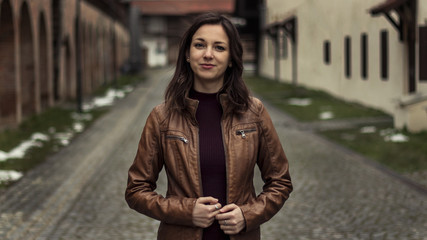portrait of a young woman in brown leather jacket outside - 200197629