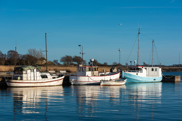 Obraz premium Old and well used fishing boats moored in harbor on a spring evening in Gronhogen on Oland, Sweden. Names and logos removed.