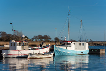 Obraz premium Old and well used fishing boats moored in harbor on a spring evening in Gronhogen on Oland, Sweden. Names and logos removed.