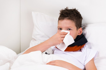 the boy lies on the bed and blows his nose in a napkin, snot after sleep