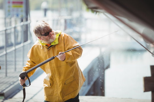 Man cleaning boat with pressure washer