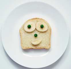 stock-photo-beautiful-food-for-breakfast-for-kids-in-the-form-of-an-open-sandwich-made-of-white-fresh-bread-yellow-banana-and-green-peas-on-the-plate-and-on-the-white-background