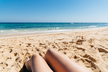 Fototapeta na wymiar Mature woman legs sunbathing on the beach