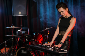 Fototapeta na wymiar Woman playing keyboard on dark stage