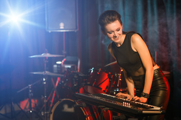 Fototapeta na wymiar Young female playing keyboards on empty stage