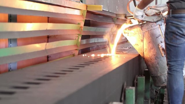 Iron molten metal pouring in sand mold ; green sand process ; industrial manufacturing equipment background