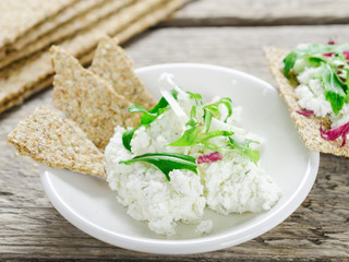 Cream cheese with greens and crisp bread on a white plate. Healthy food.