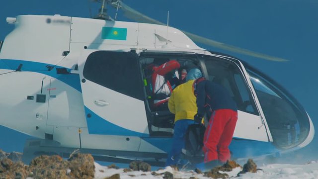 Skiers and snowboarders are disembarked from the helicopter in the mountains in winter. Close up view.
