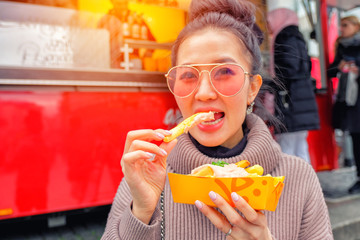 Young tourist woman eating Currywurst with French fries (Popular German Street Food), Germany