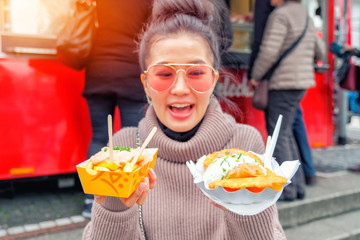 Young tourist woman eating Currywurst with French fries (Popular German Street Food), Germany