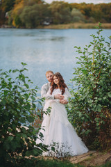 Obraz na płótnie Canvas stylish bride and groom posing on the background of the river