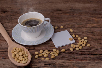 Black coffee in cups and fresh coffee beans arranged on wooden floor. And there is white paper for adding text.