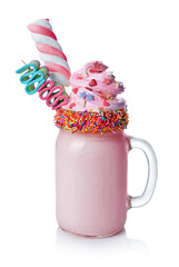 Crazy milk shake with pink whipped cream, marshmallow and colored candy in glass jar