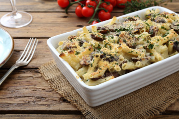 pasta gratinata maccheroni al forno con funghi e formaggio su sfondo tavolo di cucina