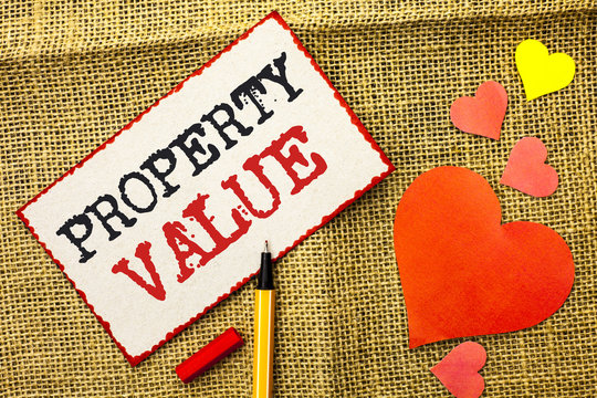Handwriting text Property Value. Concept meaning Estimate of Worth Real Estate Residential Valuation written on Sticky Note Paper by Pointer on the jute background Love Hearts next to it.