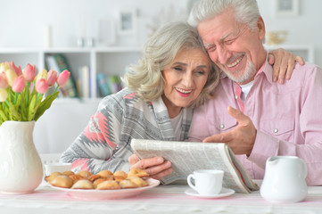 Senior couple with newspaper at home