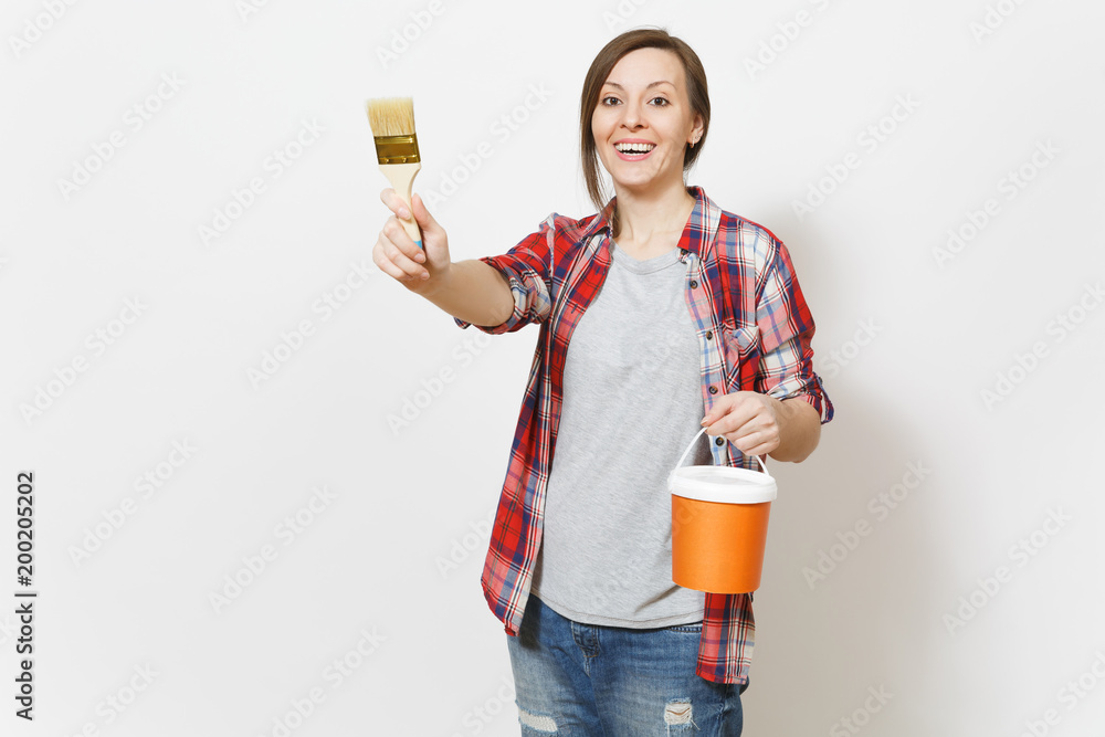 Wall mural young smiling beautiful woman holding paint bucket and pointing brush on copy space isolated on whit