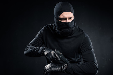 Male criminal in gloves with gun checking his watch