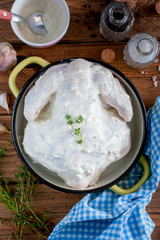 Raw whole chicken marinated in natural yoghurt with garlic and spices, top view, selective focus