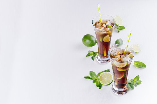 Fresh cold summer drink of cola, ice, lime, leaf mint on soft light white background, copy space, top view.