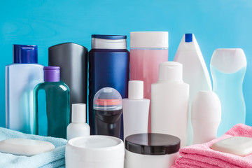 Different, colorful beauty toiletries, cream jars, soaps and towels on blue background. Body relax and care products for women and men. Front view.