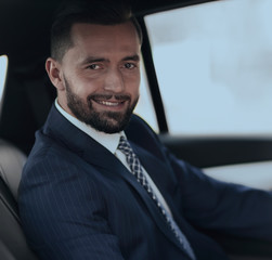 Close-up of a businessman with a laptop sitting in the car