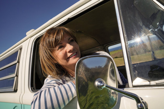 Cheerful mature woman at the steering wheel of vintage van