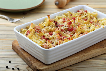 pasta gratinata maccheroni al forno con bacon e formaggio  su sfondo tavolo di cucina