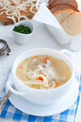 Hot homemade soup on chicken broth with homemade noodles in a white cup, selective focus