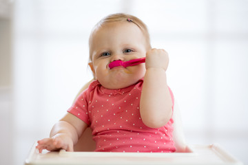 Funny infant baby girl spoon eats itself