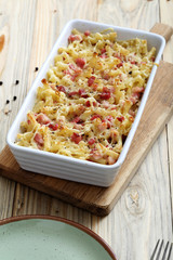 pasta gratinata maccheroni al forno con bacon e formaggio  su sfondo tavolo di cucina