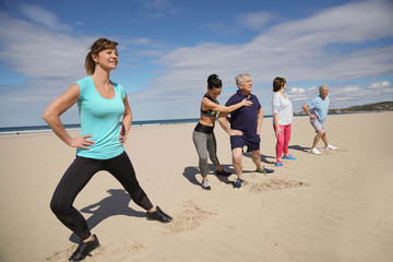 Senior people exercising on the beach with sports coach