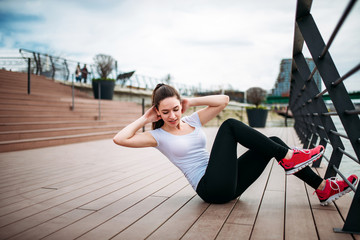 Abs workout outdoors. Beautiful girl exercising at city quay.