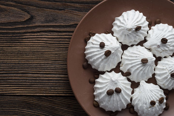 Sweet dessert - vanilla marshmallow (zephyr) on a wooden table with coffee beans, selective focus.