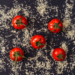 grated parmesan cheese and tomatoes on black background