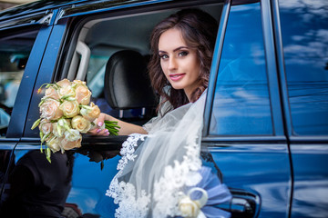 Beautiful bride in wedding dress peeking out of car window
